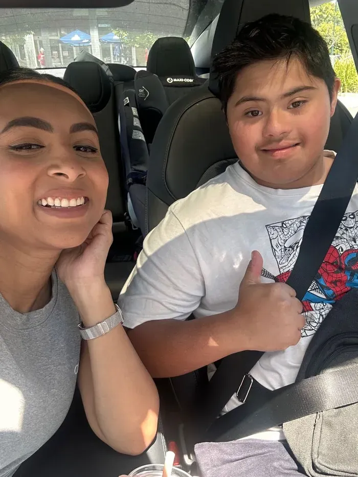 A support worker and participant sharing a smile and a thumbs-up in the car